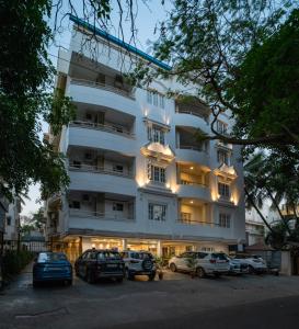 un bâtiment blanc avec des voitures garées dans un parking dans l'établissement Hyde Park Orchards, à Bangalore