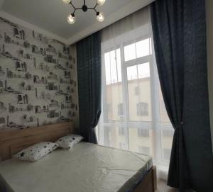 a bedroom with a bed and a large window at Polaris plus in Bishkek