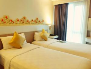 Cette chambre comprend 2 lits et une fenêtre. dans l'établissement All Nite & Day Hotel Yogjakarta - Gejayan, à Yogyakarta