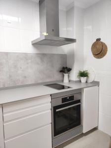La cuisine est équipée de placards blancs et d'un four avec plaques de cuisson. dans l'établissement KOA Centric, comfy in Ruzafa, à Valence