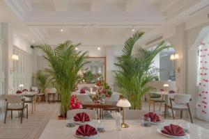 a restaurant with tables and chairs and palm trees at Hotel Thomas Bangkok in Makkasan