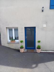 eine blaue Tür und zwei Topfpflanzen vor einem Gebäude in der Unterkunft Studio calme in Pleine-Fougères