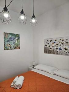 1 dormitorio con 1 cama con 2 toallas y 2 luces en Guest House Aio Sardegna, en Cagliari