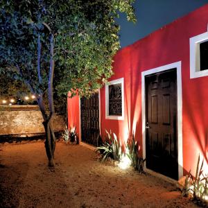a red building with a black door and a tree at Colonial Villa in Merida Centro 4BR 3BA Private Pool Near Paseo de Montejo in Mérida