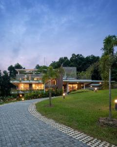 a large house with a cobblestone road in front of it at Premium 5 BR full pool villa by lake close to Vagamon in Muttam