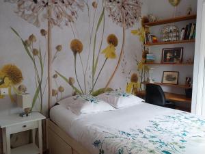 a bedroom with a bed with flowers on the wall at Domyv'Loup in Entrevaux