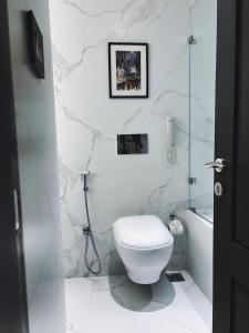 a white bathroom with a toilet and a bath tub at Peerless Hotel Kolkata in Kolkata