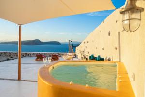 a yellow swimming pool with an umbrella and the ocean at Akron Terra Houses in Akrotiri