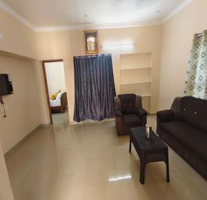 a living room with a couch and a chair and a table at Arumugam Residency AC in Tiruchchendūr