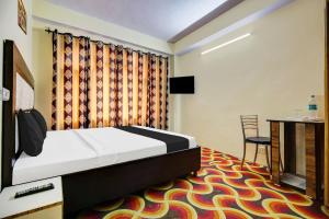 um quarto com uma cama, uma mesa e uma cadeira em OYO Hotel Basera em Shimla