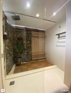 a bathroom with a stone wall and a glass wall at The Green Lagoon in Pantai Cenang