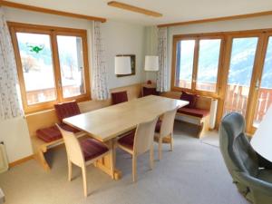 a dining room with a table and chairs and windows at Ferienwohnung Fernblick in Bellwald