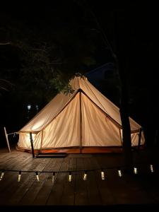 a white tent sitting on a wooden deck at night at Glamping Cisnadioara in Cisnădioara