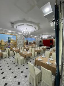 a restaurant with tables and chairs and a chandelier at Shosh Garden Family Resort in Chorwoq