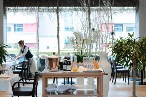 Una mujer en una habitación con una mesa con botellas de vino. en Senevita Residenz & Apartments Muri bei Bern, en Berna