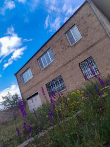 a brick building with windows and purple flowers at GUEST HOUSE SG in Norakert