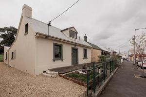 a white house with a fence in front of it at Cavell Street Cottage in West Hobart in Hobart