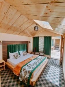a bedroom with a large bed with green curtains at The Grand Lodge Pangong in Lukung