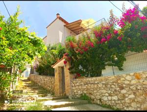 a house with flowers on a stone wall at Bourbos Summer Rooms in Himare