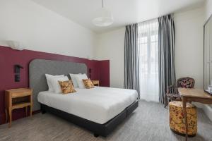 ein Hotelzimmer mit einem Bett und einem Schreibtisch in der Unterkunft Hôtel de la Poste in Beaune