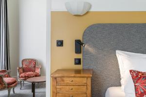 um quarto com uma cama, uma cadeira e uma cómoda em Hôtel de la Poste em Beaune