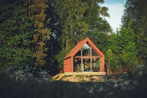 ein kleines rotes Haus mit einem großen Glasfenster in der Unterkunft Private cabin in the middle of nature 