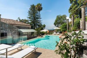 a swimming pool with tables and chairs in front of a building at Villa Voces in Catania