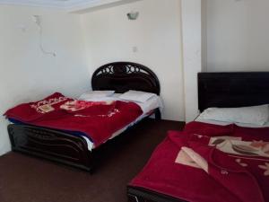 2 Betten in einem Zimmer mit roten Decken darauf in der Unterkunft Murree Continental Hotel in Murree