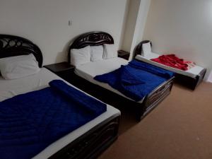 2 Einzelbetten in einem Zimmer mit blauer Bettwäsche in der Unterkunft Murree Continental Hotel in Murree