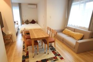 a living room with a dining room table and a couch at Apartment Hotel Tenjin TUMUGU in Fukuoka