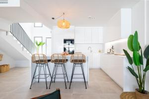 Una cocina con gabinetes blancos y taburetes de bar. en Luxury House Chaparral Golf E48 by AORA STAY, en La Cala de Mijas