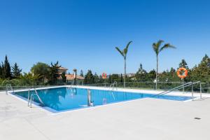 una piscina con agua azul y palmeras en Luxury House Chaparral Golf E48 by AORA STAY, en La Cala de Mijas