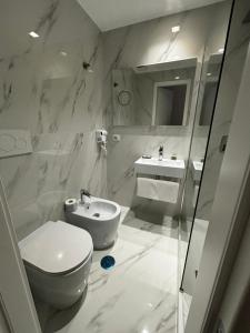a white bathroom with a toilet and a sink at Hotel Gabriella in Rome