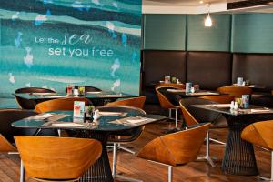 a dining room with tables and chairs and a chalkboard at Hotel Baraquda Heeton Pattaya by Compass Hospitality in Pattaya