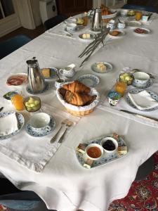 een tafel met een witte tafeldoek met voedsel erop bij Chambres d'Hôtes les Charmettes in Étretat