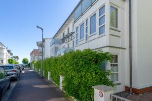 ein weißes Gebäude mit einem Busch neben einer Straße in der Unterkunft Haus "Concordia" in Binz - WG 02 "Seedorf" mit Terrasse, strandnah in Binz