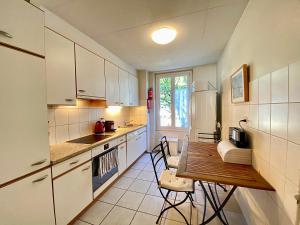 a kitchen with a wooden table and a table and chairs at Very nice apartment close to the lake in Lausanne
