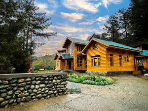 a log cabin with a stone wall in front of it at Dawat-e-Drung by FrozenFall Resort in Gulmarg