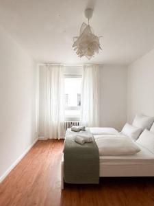 a white bedroom with a bed and a chandelier at NOOK Design Apartments with Kitchen in Berlin
