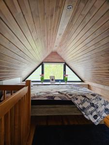 Bett in einem kleinen Zimmer mit einem großen Fenster in der Unterkunft Domek na korcie in Lubomierz