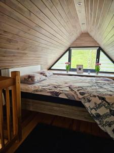 Bett in einem Zimmer mit einem großen Fenster in der Unterkunft Domek na korcie in Lubomierz