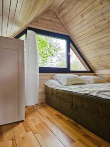 Bett in einem kleinen Zimmer mit Fenster in der Unterkunft Domek na korcie in Lubomierz