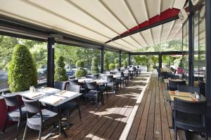 a restaurant with tables and chairs on a deck at ibis Marne La Vallee Champs-sur-Marne in Champs-Sur-Marne
