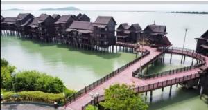 een rij huizen op een dok in het water bij The Green Lagoon in Pantai Cenang