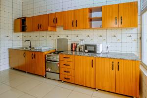 een keuken met houten kasten, een wastafel en een magnetron bij Kigali Wings Apartment 4 in Kigali