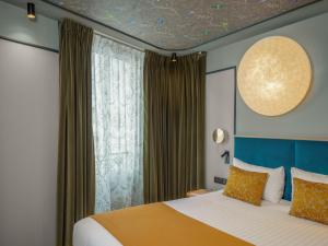 a bedroom with a bed and a large window at Hotel Louison in Paris