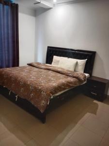 a bedroom with a bed with a brown comforter at AL KHALEEJ HOTEL in Murree