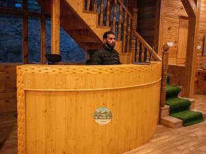 a man sitting at a podium in a wooden cabin at Dawat-e-Drung by FrozenFall Resort in Gulmarg