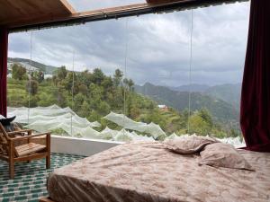 ein Schlafzimmer mit einem Bett und einem großen Fenster in der Unterkunft Stargazing Glass Lodge Himachal Pradesh Thachi in Mandi