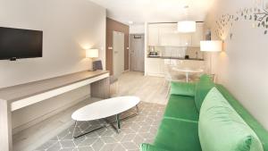 a living room with a green couch and a kitchen at Bormio - Czarna Góra Resort by Sun & Snow z nielimitowanym basenem in Sienna